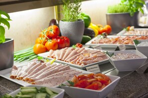 Un buffet proposant une variété de plats, notamment des viandes en tranches, des légumes et des salades.