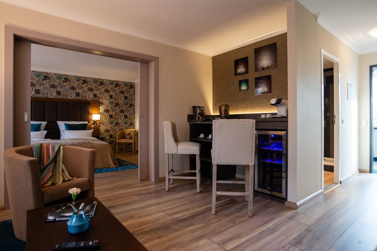 Una habitación de hotel con una cama, dos sillas, un escritorio con una computadora y un acuario.