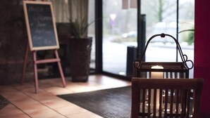 Una silla de madera con una vela en su interior, una pizarra con escritura y una planta en maceta.