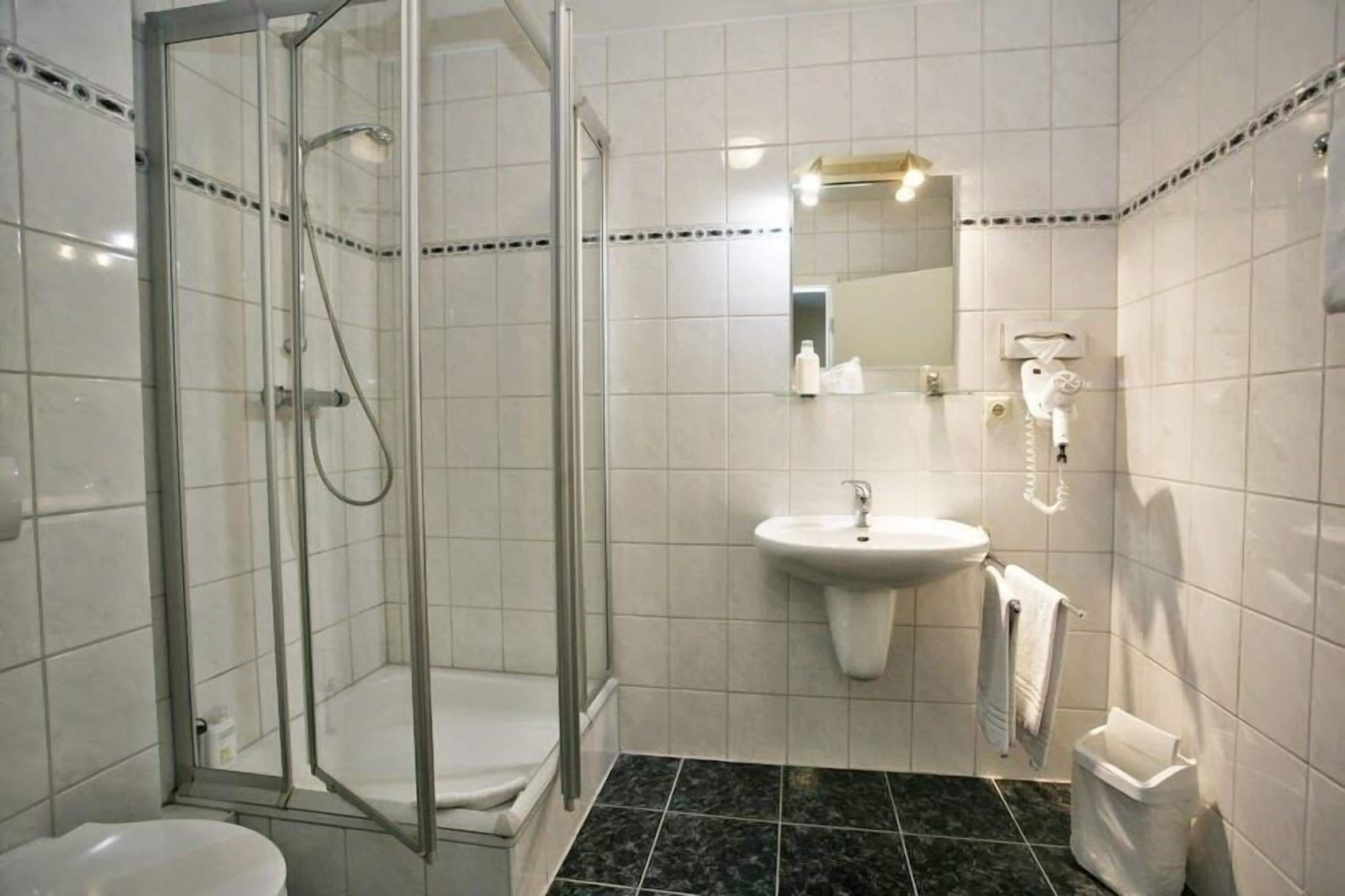 Un baño moderno con ducha de vidrio, lavamanos e inodoro.
