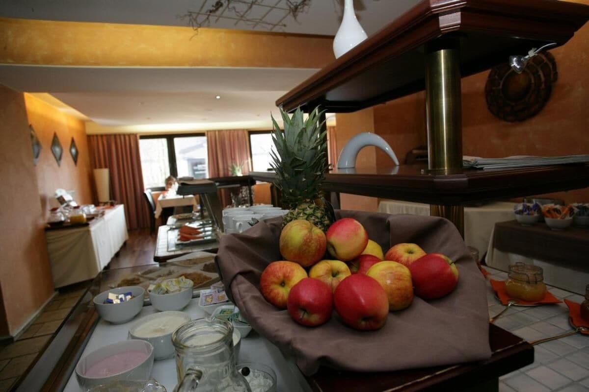 A breakfast buffet with a variety of fruits, including apples and a pineapple, and several bowls of food and condiments.