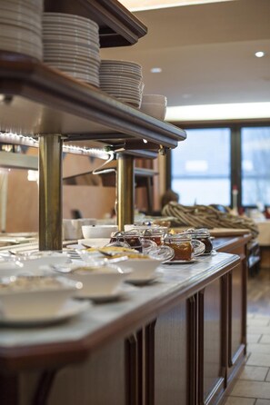 A buffet setup with plates, bowls, and jars of condiments. - Stargaze Home Hotel (Haan)