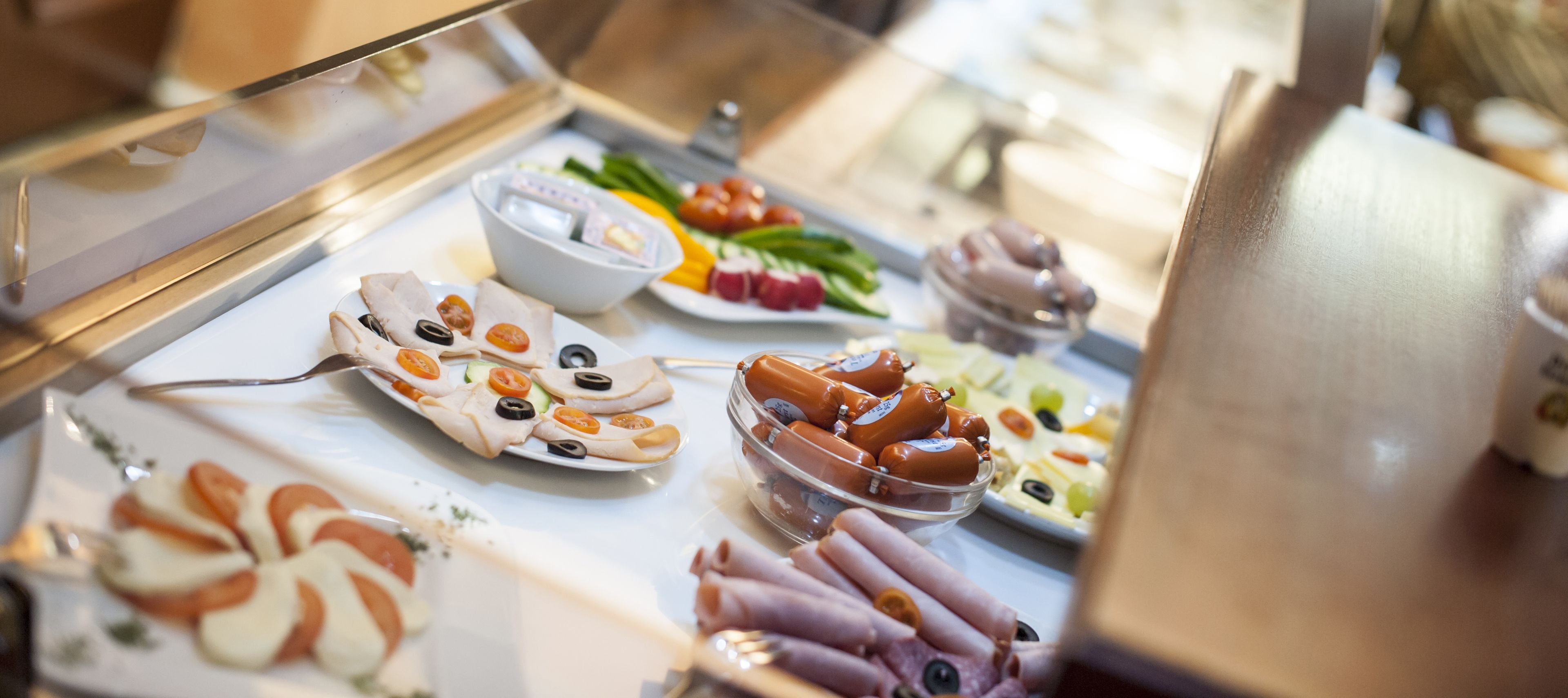 A buffet with various food items including sliced meats, cheeses, and vegetables.