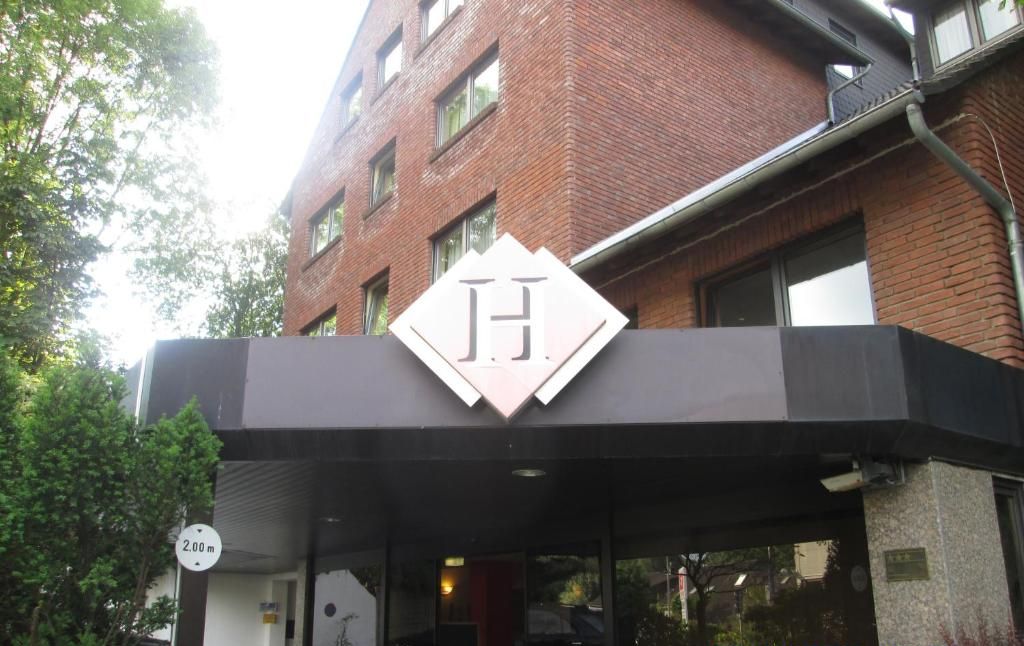 En hotellentrén med en tydlig logotyp i form av bokstaven ”H”, ett överbyggt entréområde och en skylt som är 2,00 meter hög.