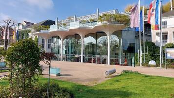 A modern building with a glass facade and a covered outdoor area with benches.