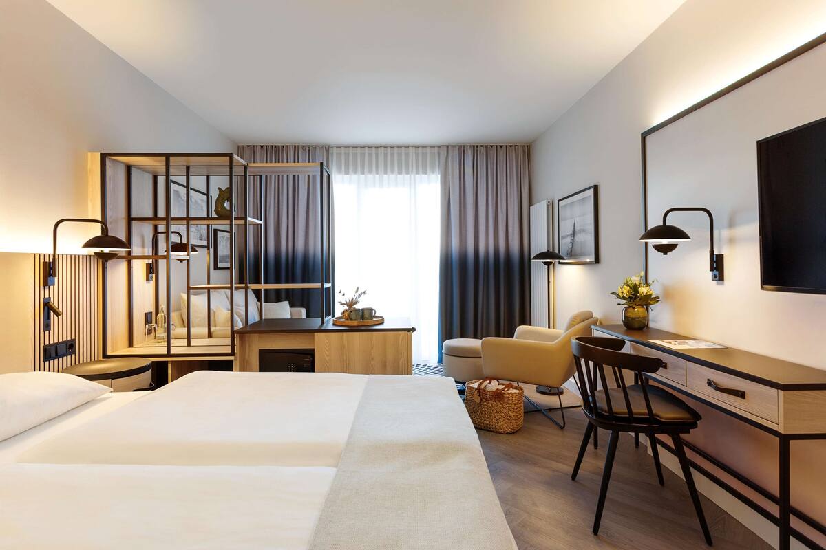 Une chambre d’hôtel avec deux lits, un bureau avec une chaise, une petite table et un téléviseur.