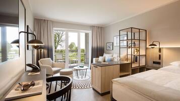 Habitación de hotel con cama, escritorio, silla, una mesita y balcón con vistas.