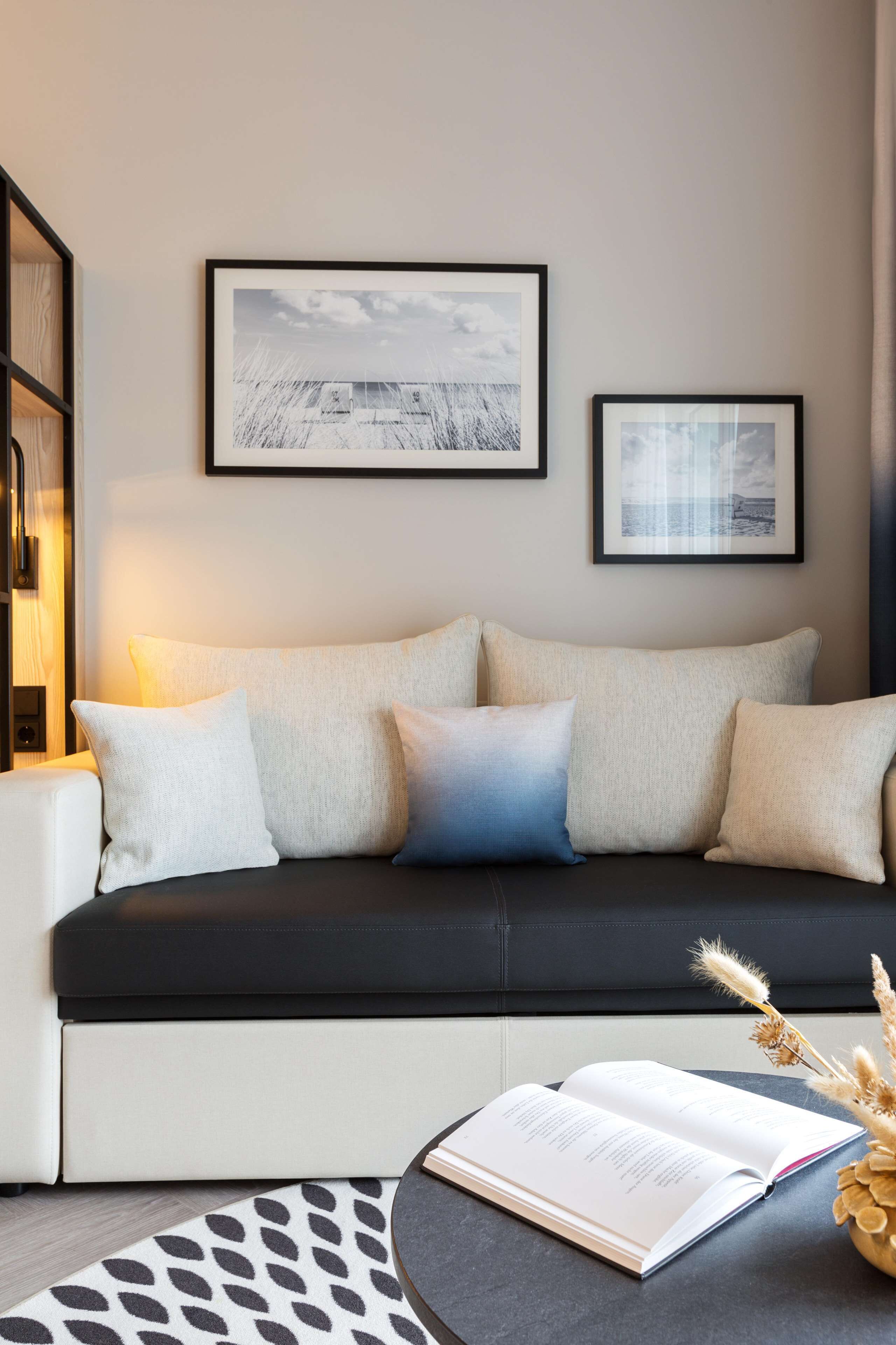 A modern living room with a sofa, a side table, and two framed pictures on the wall.