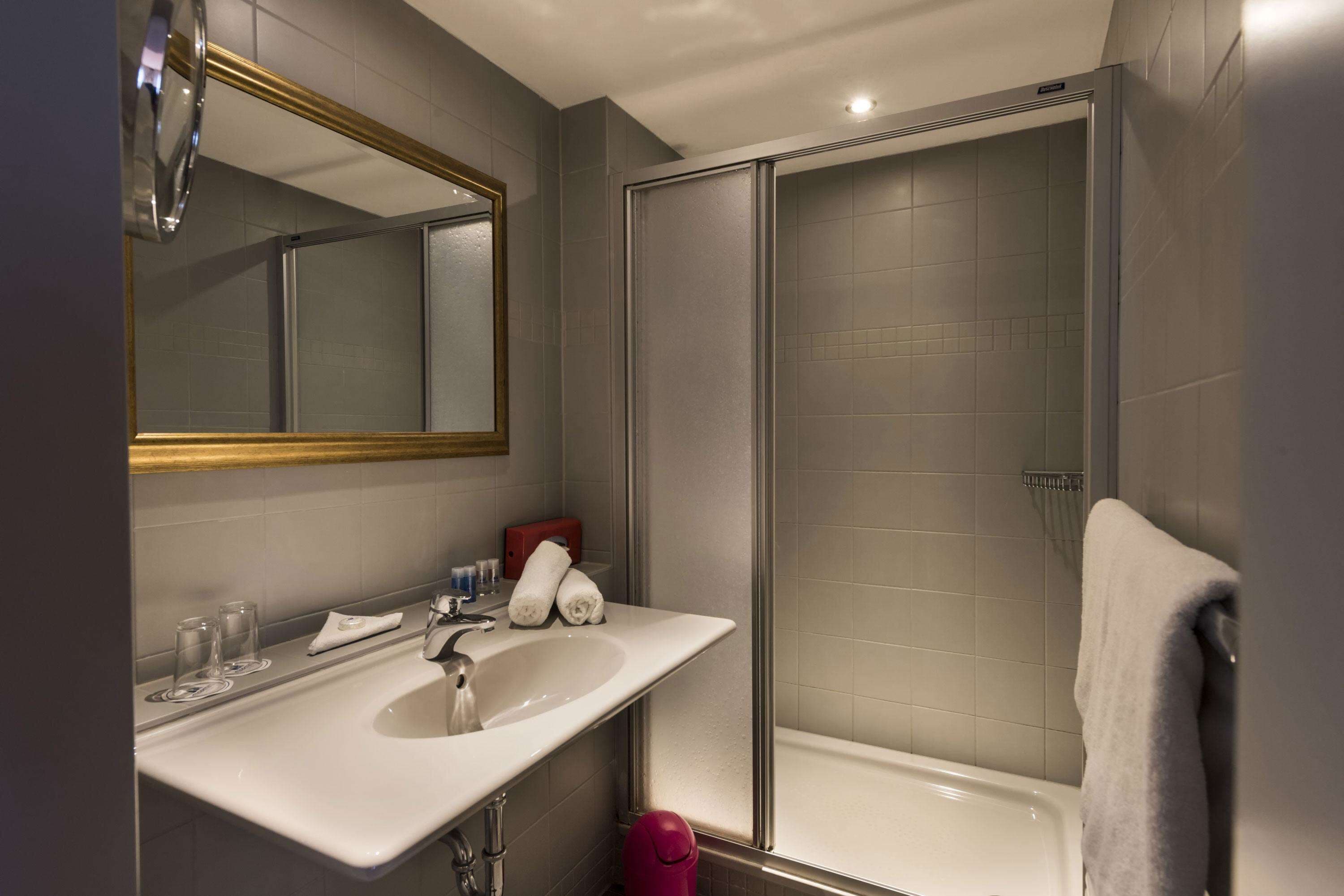 Un bagno moderno con uno specchio grande, un lavandino e una zona doccia.