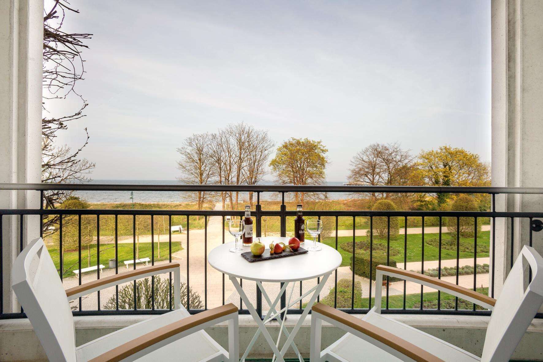 A balcony with a white table and chairs, a bottle of wine, and a glass of wine.