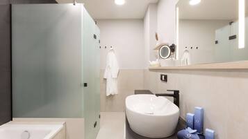Un baño moderno con una bañera independiente, un lavabo grande y redondo, y un mueble de tocador con espejo y artículos de aseo.