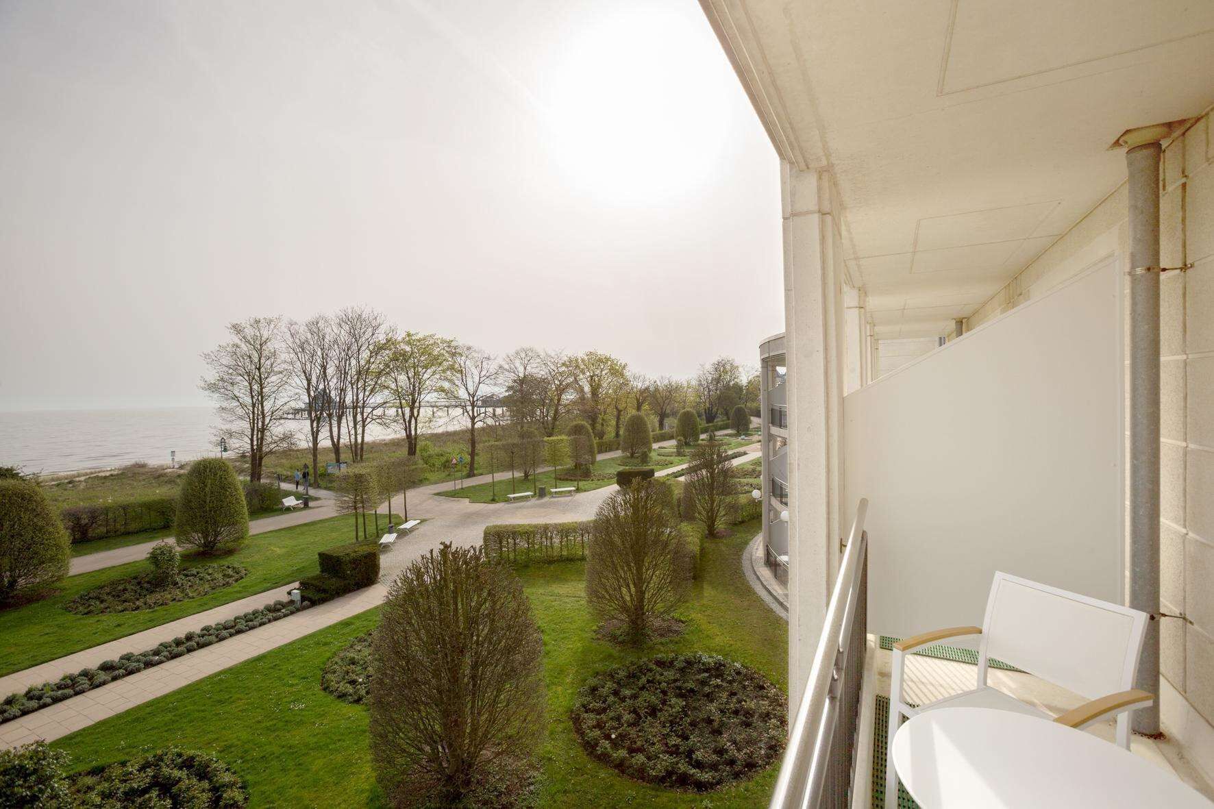 Ein Balkon mit Blick auf einen angelegten Garten und ein Gewässer.