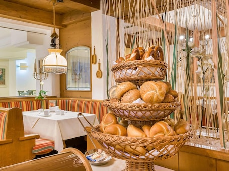 A dining area with a three-tiered bread basket, wooden furniture, and a hanging light fixture.