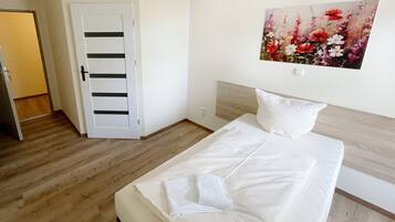 Een hotelkamer met een bed, een bloemenstilleven aan de muur en een deur met strepen.