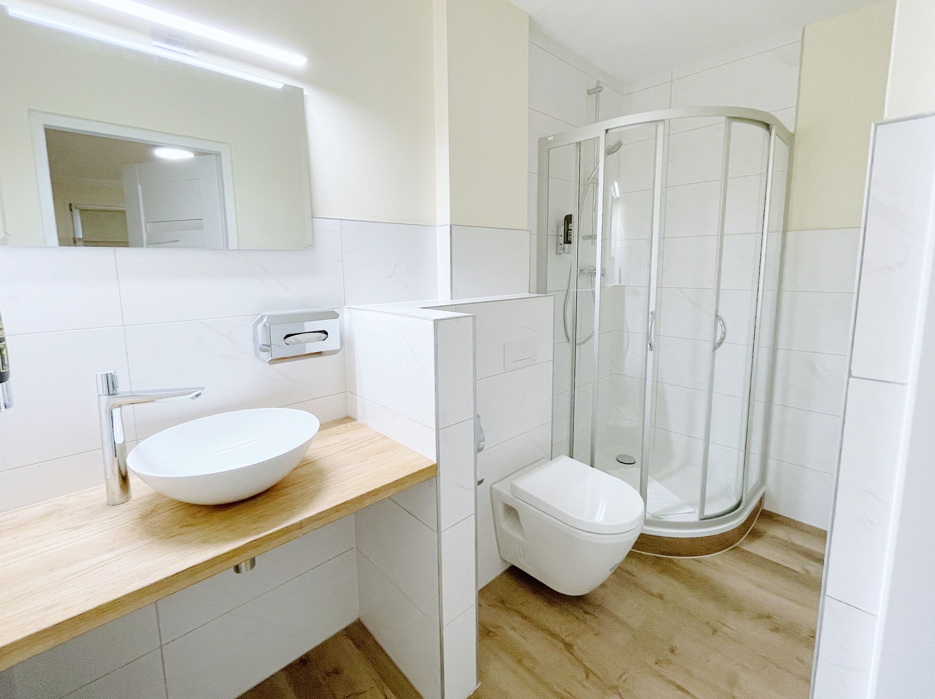 A modern bathroom with a white sink, toilet, and glass shower enclosure.