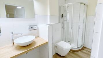 A modern bathroom with a white sink, toilet, and glass shower enclosure.