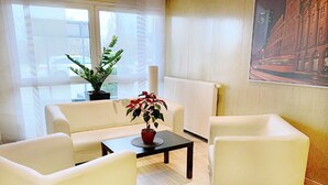 A modern living room with a sofa, two armchairs, a coffee table, and a potted plant. - REGIOHOTEL Leipzig West (Schkeuditz)