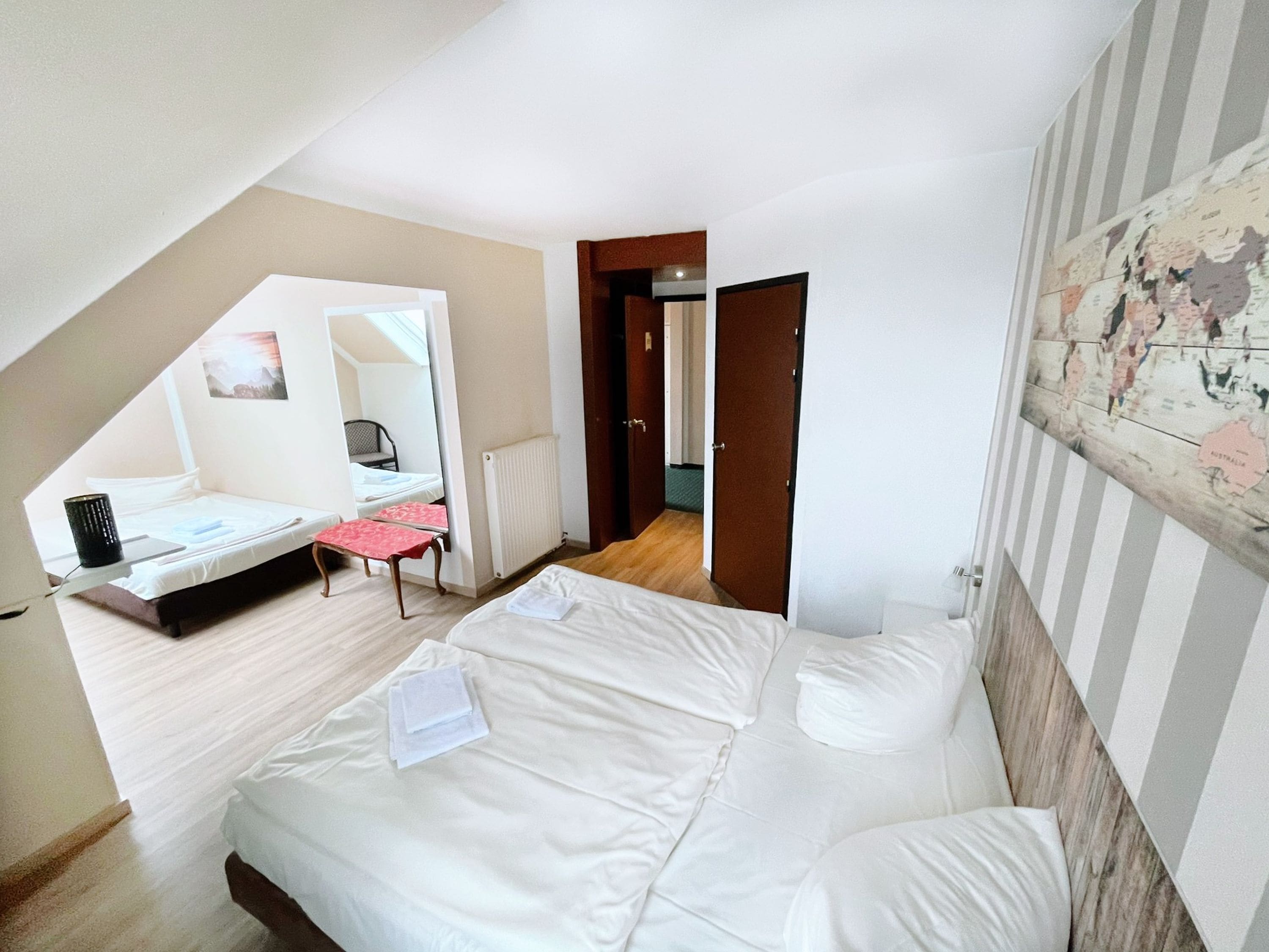 A bedroom with a bed, a desk, a chair, and a map on the wall.