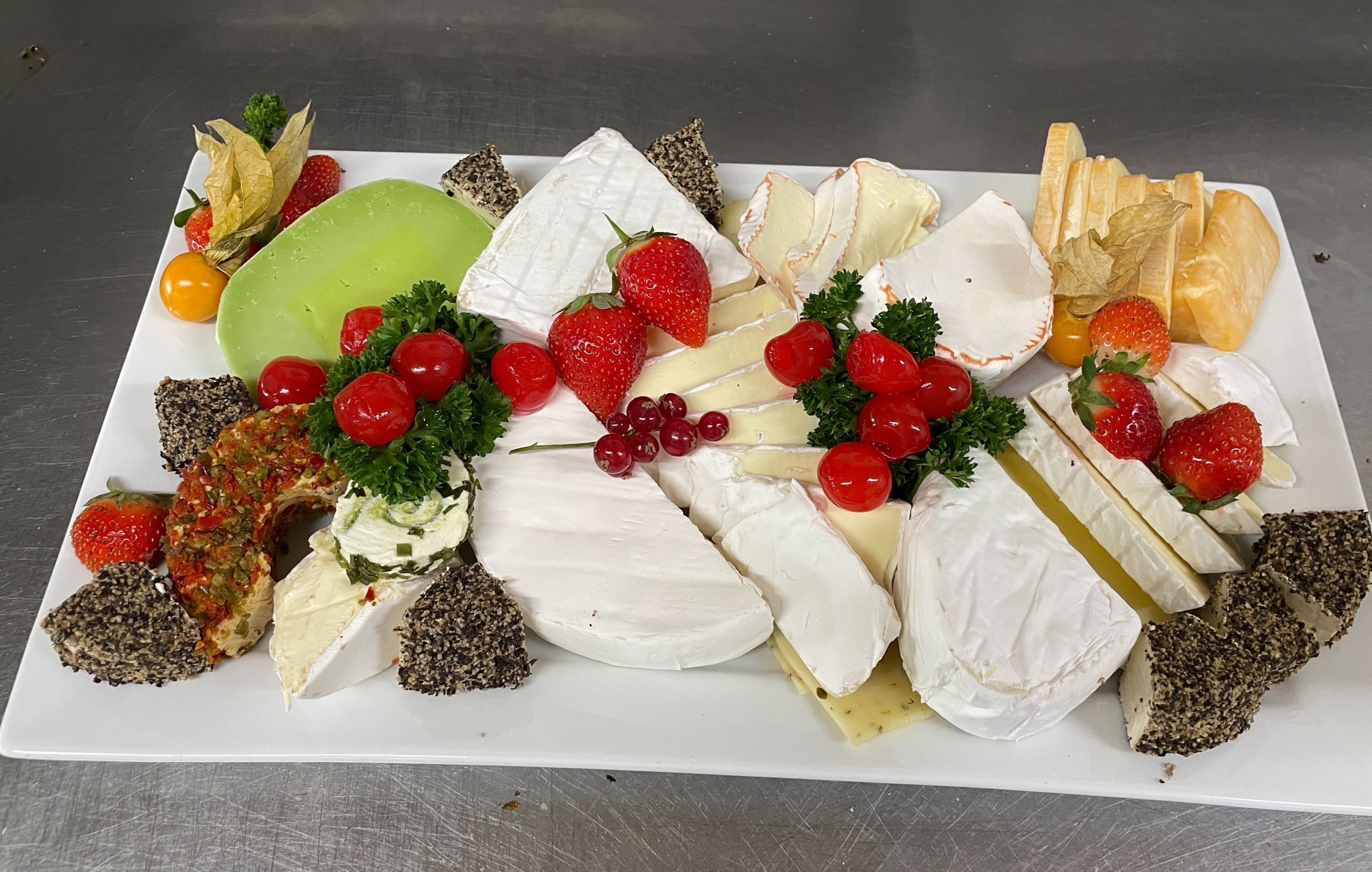 A charcuterie board with various cheeses, fruits, and crackers.