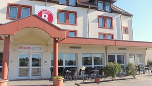 A hotel with a prominent "HOTEL" sign, outdoor seating area, and a clear view of the entrance. - REGIOHOTEL Leipzig West (Schkeuditz)
