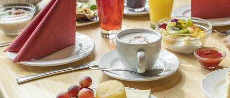 A breakfast setting with plates of food, a cup of coffee, and various beverages.