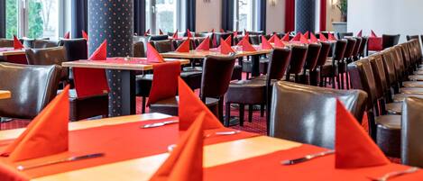 A restaurant with rows of tables, each with red napkins and cutlery.
