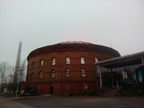 Un edificio de ladrillo grande con una sección central circular y una torre alta al fondo.