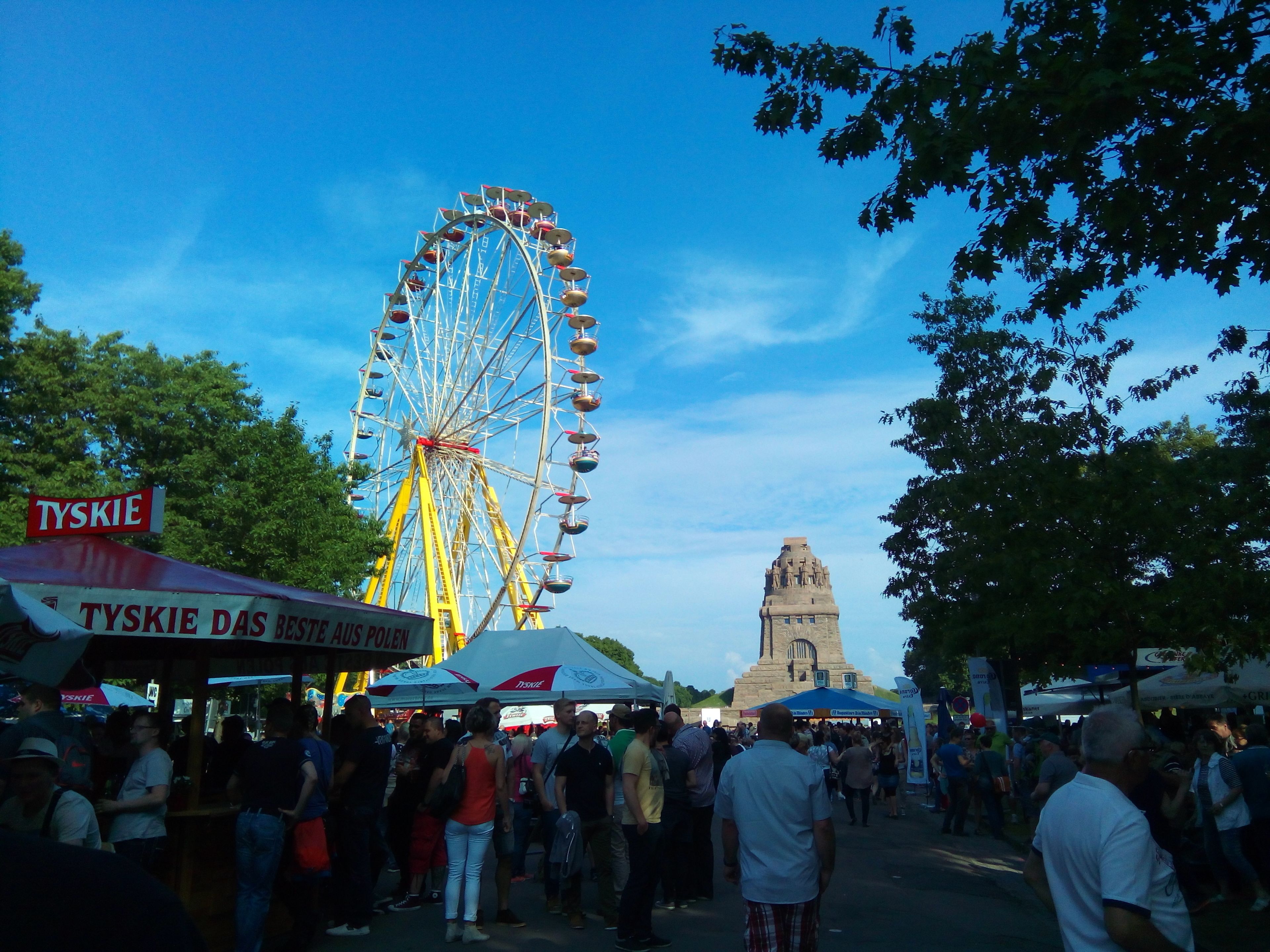 A Ferris wheel and a crowd of people at an outdoor event.