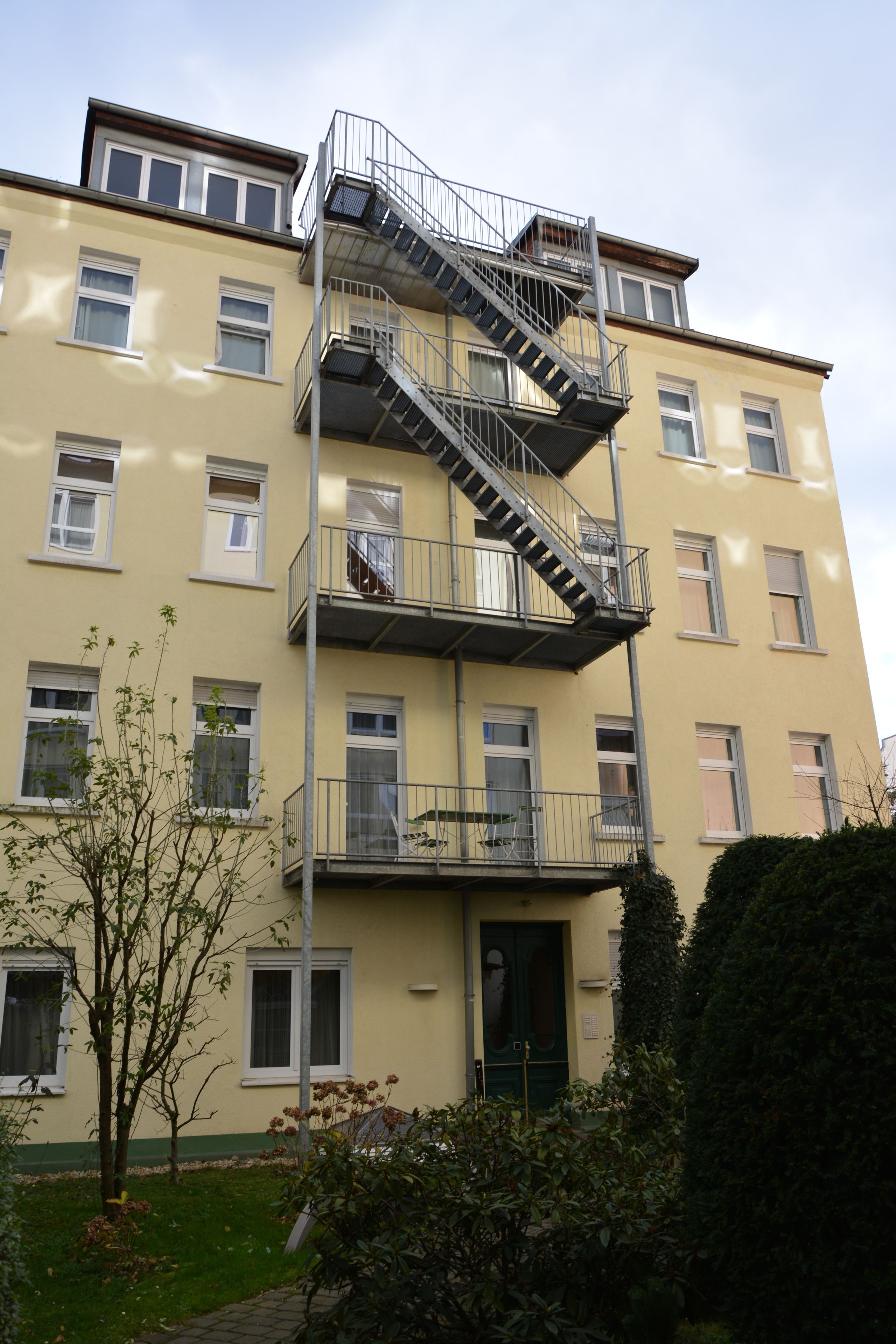 A multi-story building with a fire escape, balconies, and a green door.