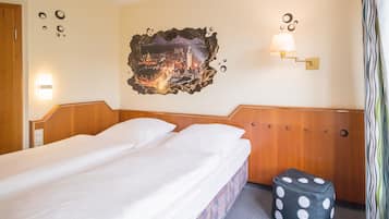 Une chambre d’hôtel avec un lit parfaitement fait, un tableau représentant un paysage urbain accroché au mur, une lampe murale et un pouf à pois.