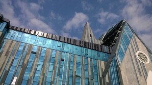 Un bâtiment moderne doté de grandes fenêtres en verre réfléchissant et d’un imposant clocher.
