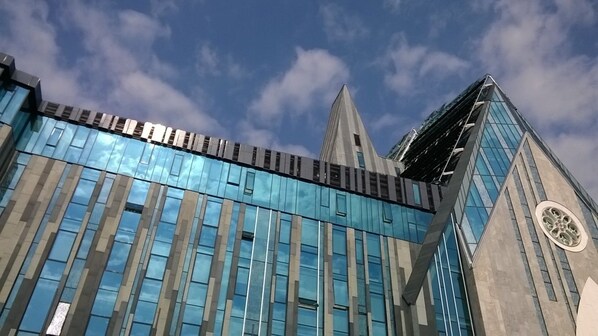 Un edificio moderno con ventanas de vidrio reflectante y una destacada torre de reloj.