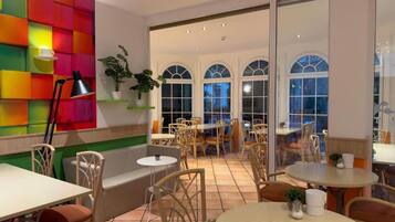 A hotel room with a colorful wall, multiple seating areas, and large windows.