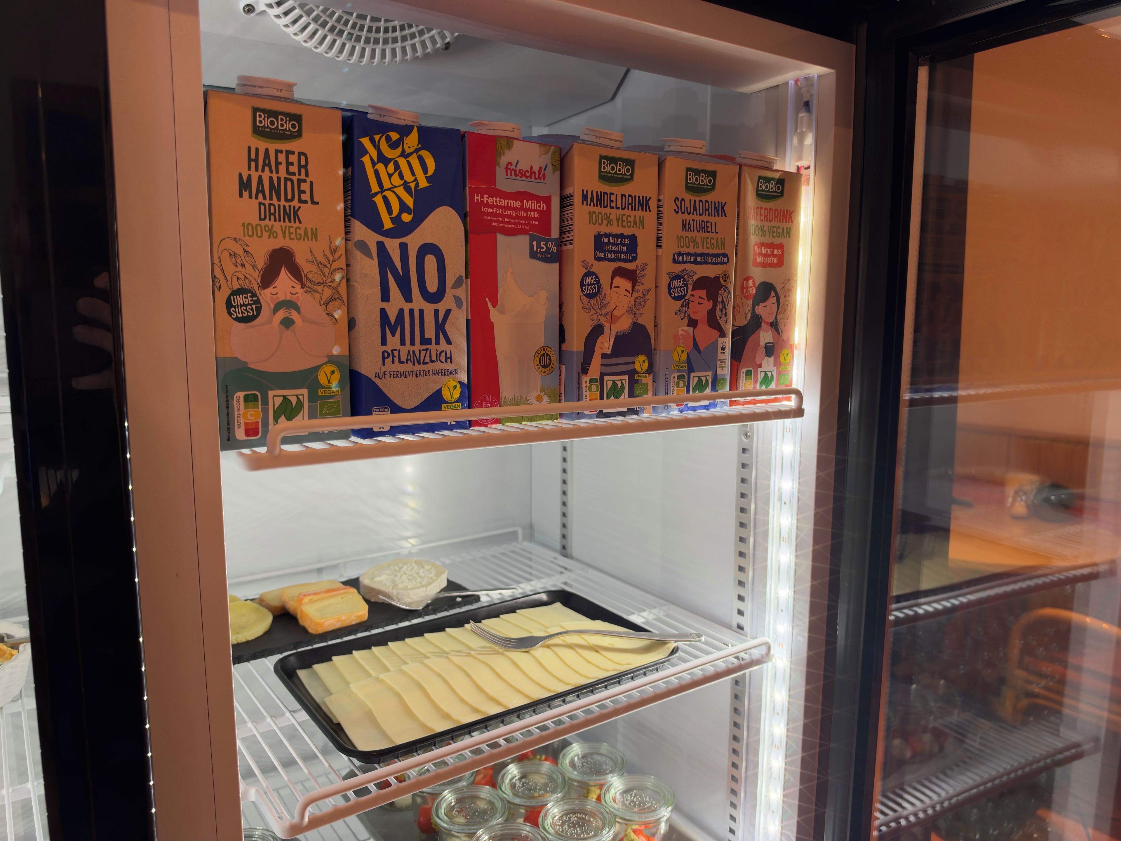 Un refrigerador lleno de diferentes cartones de leche vegana y a base de plantas.