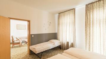 A hotel room with a single bed, a chair, a small table, and a wall-mounted artwork.