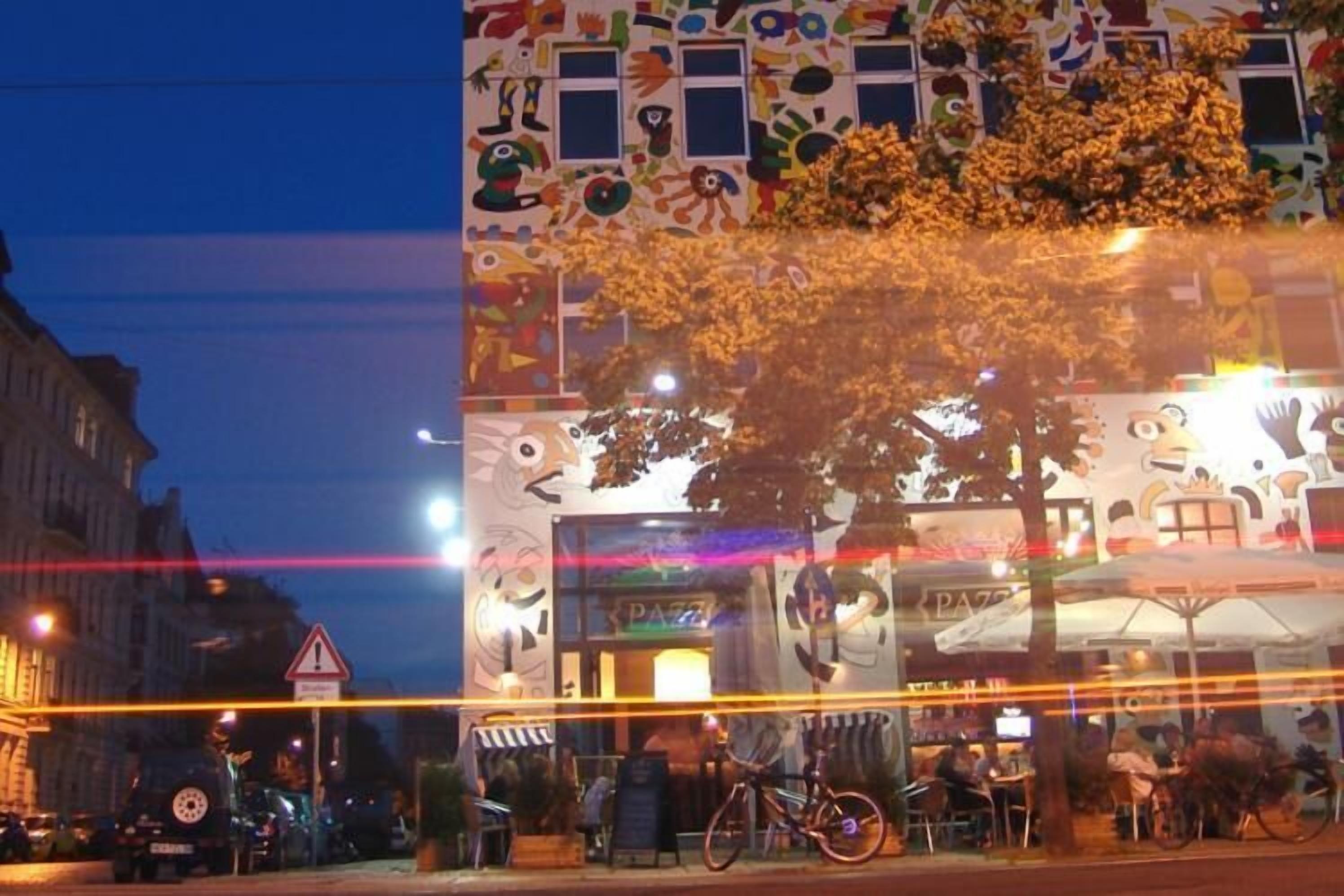 A building with a colorful facade and a tree in front.
