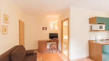 A compact living space with a kitchenette, a small dining area, and a sofa.