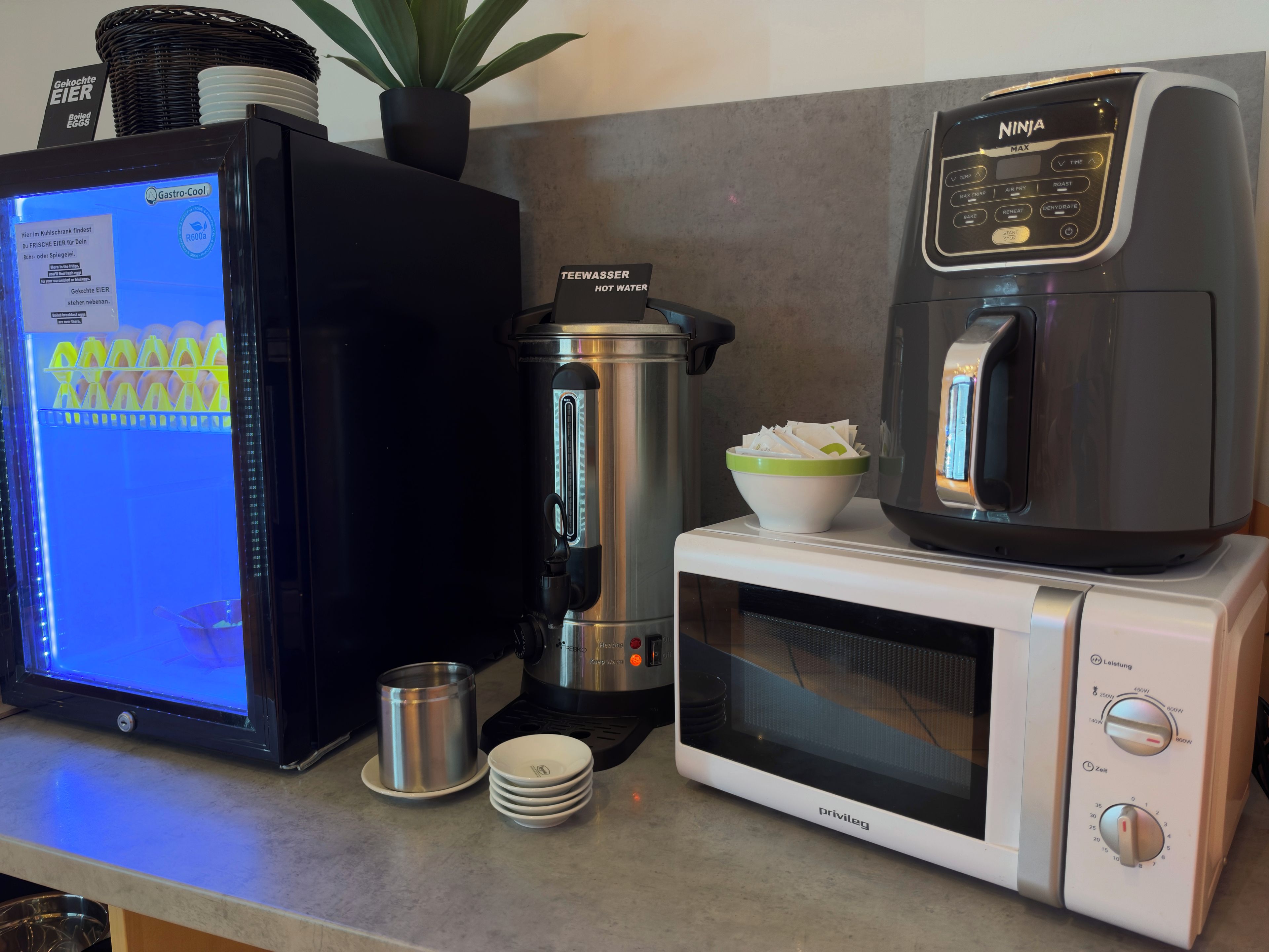 A kitchen with a coffee maker, a microwave, a kettle, and a digital scale.