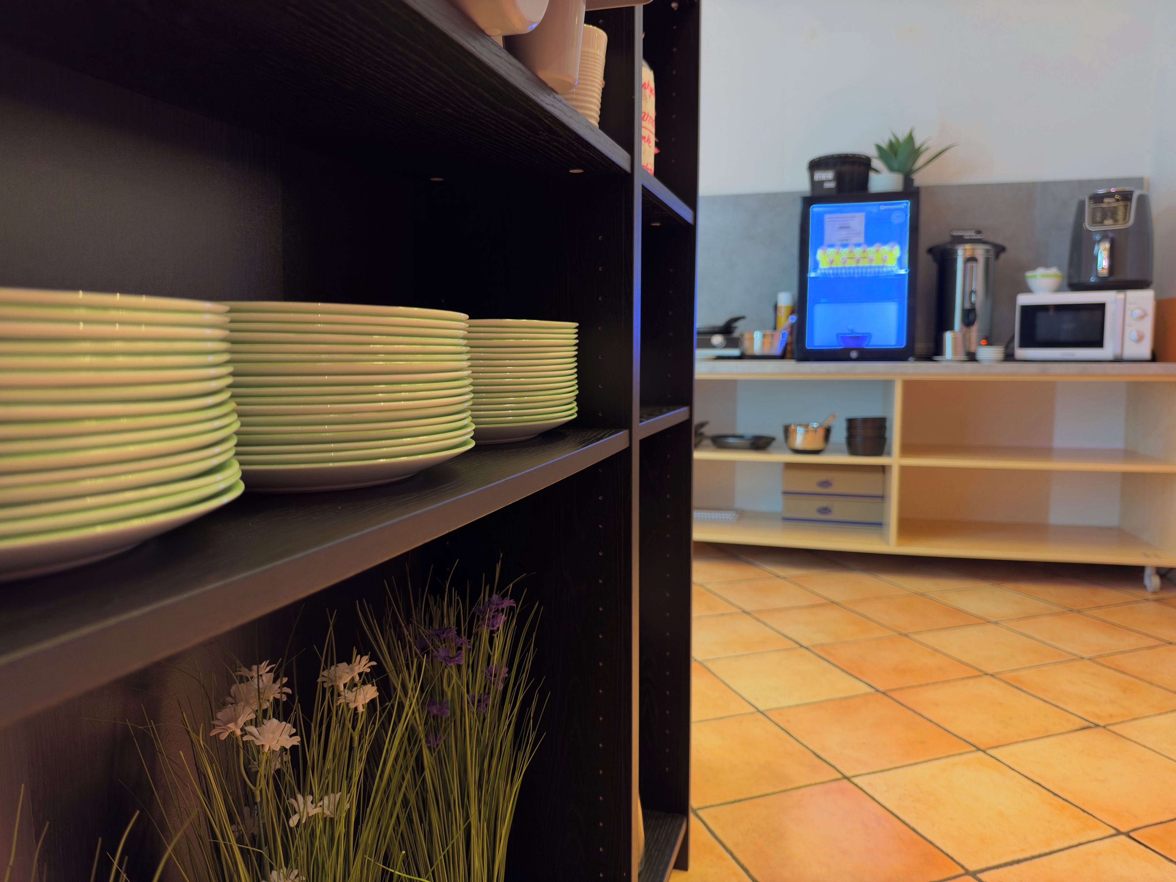 A kitchen with a microwave, coffee maker, and a computer monitor on the counter.