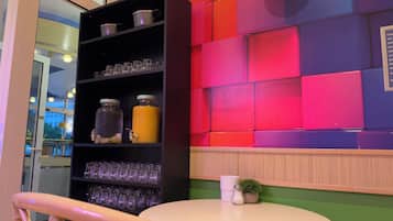 Una habitación con una mesa redonda, un estante con frascos, y una pared colorida.