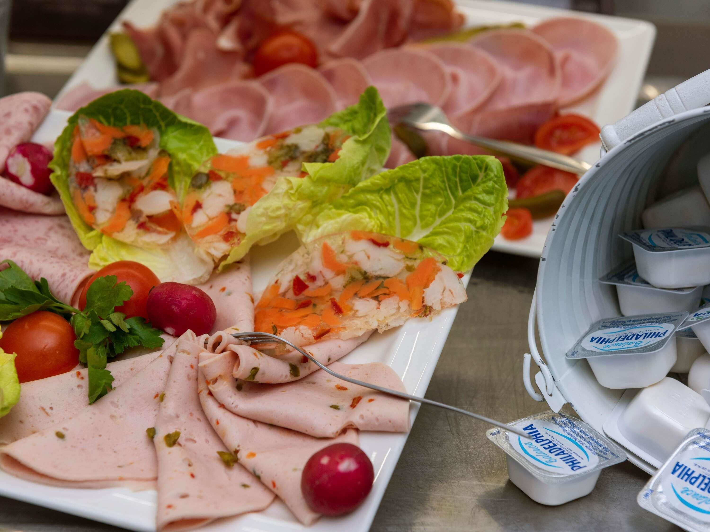 A buffet with various food items including sliced meats, salads, and dairy products.