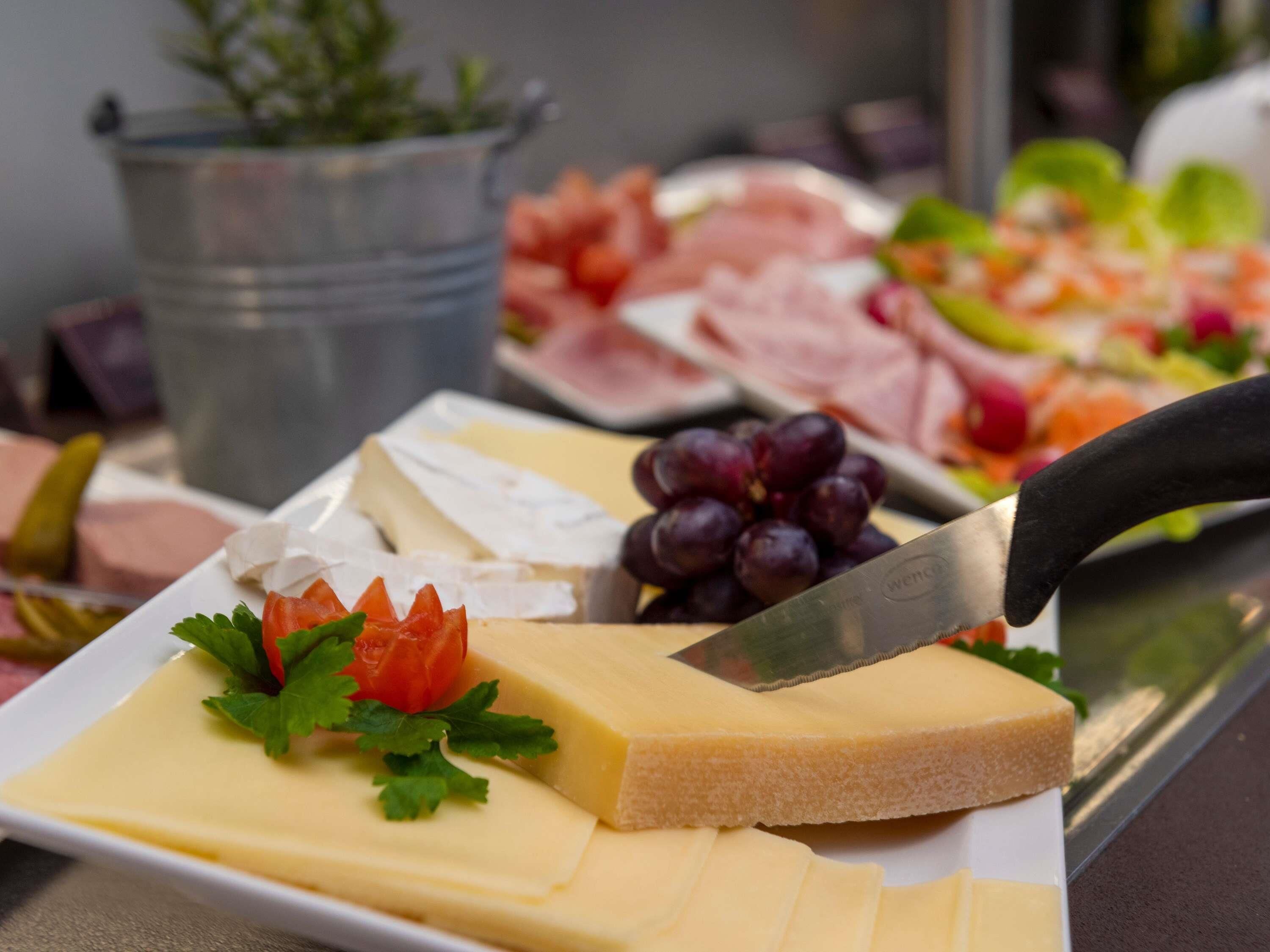 Una tabla de fiambres con quesos, carnes y frutas variadas.