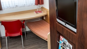Une chambre avec un lit superposé, un bureau, une chaise, un téléviseur et un porte-revues.