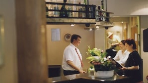 A bar area with stools, a counter, and a shelf with bottles. - Hotel Jedermann (Munich)