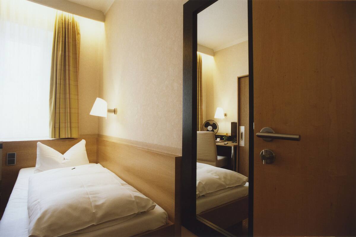 Habitación de hotel con dos camas, un escritorio, una silla, una lámpara y un espejo.