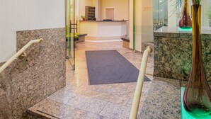 Eine moderne Hotelhalle mit einer Rezeption, einem Wartebereich und einer Treppe mit Geländern.