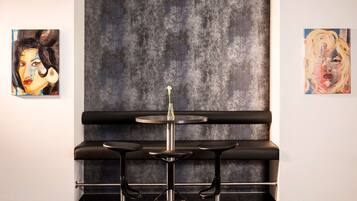 Un espace bar au design moderne, avec un comptoir et des tabourets noirs, et deux œuvres d’art accrochées aux murs.