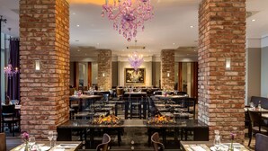 A spacious restaurant with brick walls, multiple dining tables, and a chandelier. - Dorint Kongresshotel Düsseldorf/Neuss (Neuss)