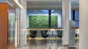 A modern lobby with a green wall, three black chairs, and a reception desk. - Dorint Kongresshotel Düsseldorf/Neuss (Neuss)