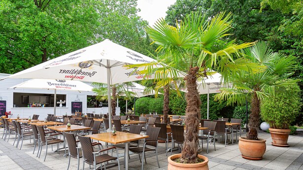 An outdoor cafe with tables and chairs, large umbrellas, and potted plants. - Dorint Kongresshotel Düsseldorf/Neuss (Neuss)